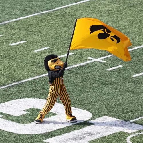I-Club Membership mascot posing waving flag on football field